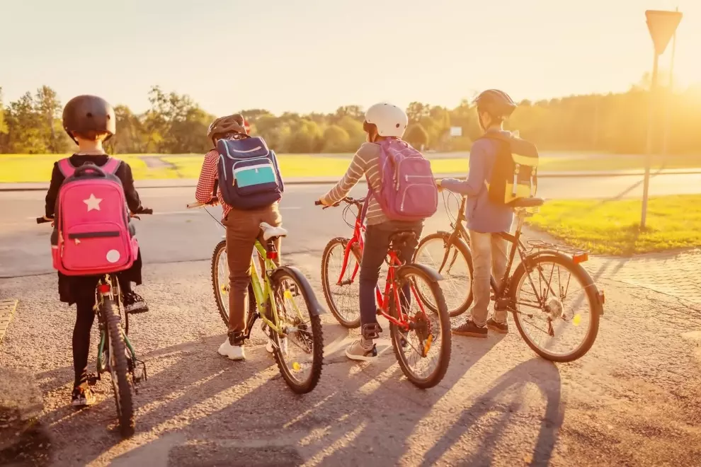 Student riding a bicycle to school on a rural road.