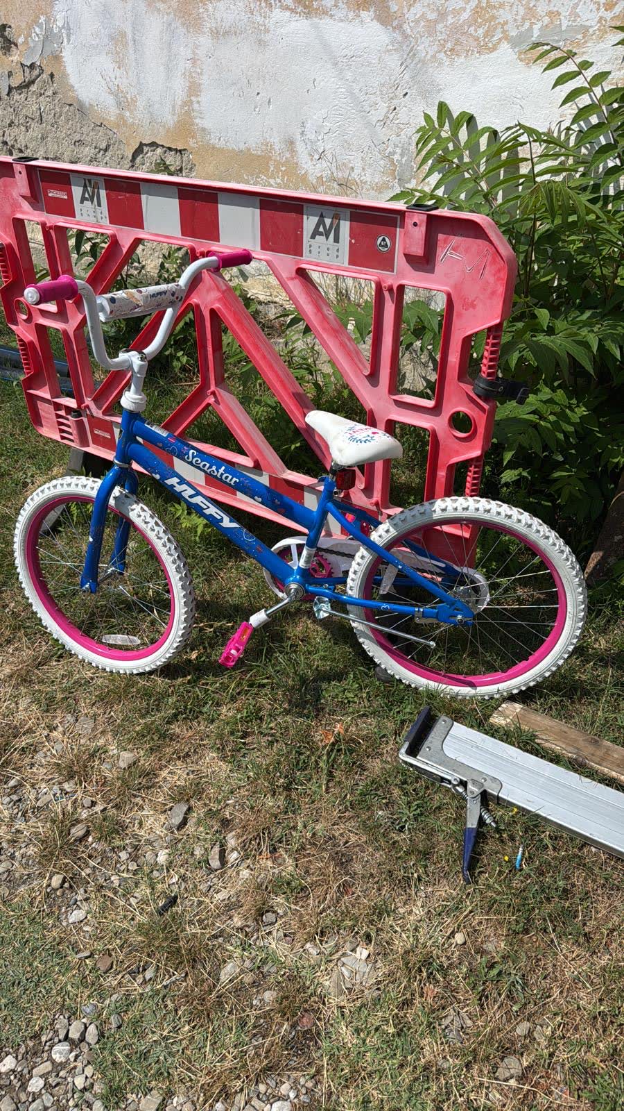 A blue and pink bicycle propped against a road barrier.