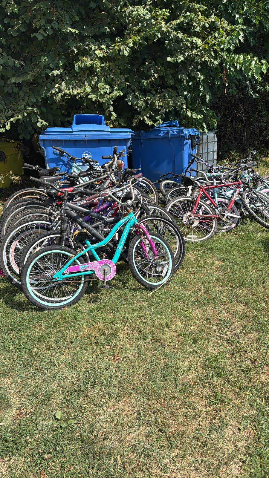 A teal and pink bicycle among a cluster of donated bikes.