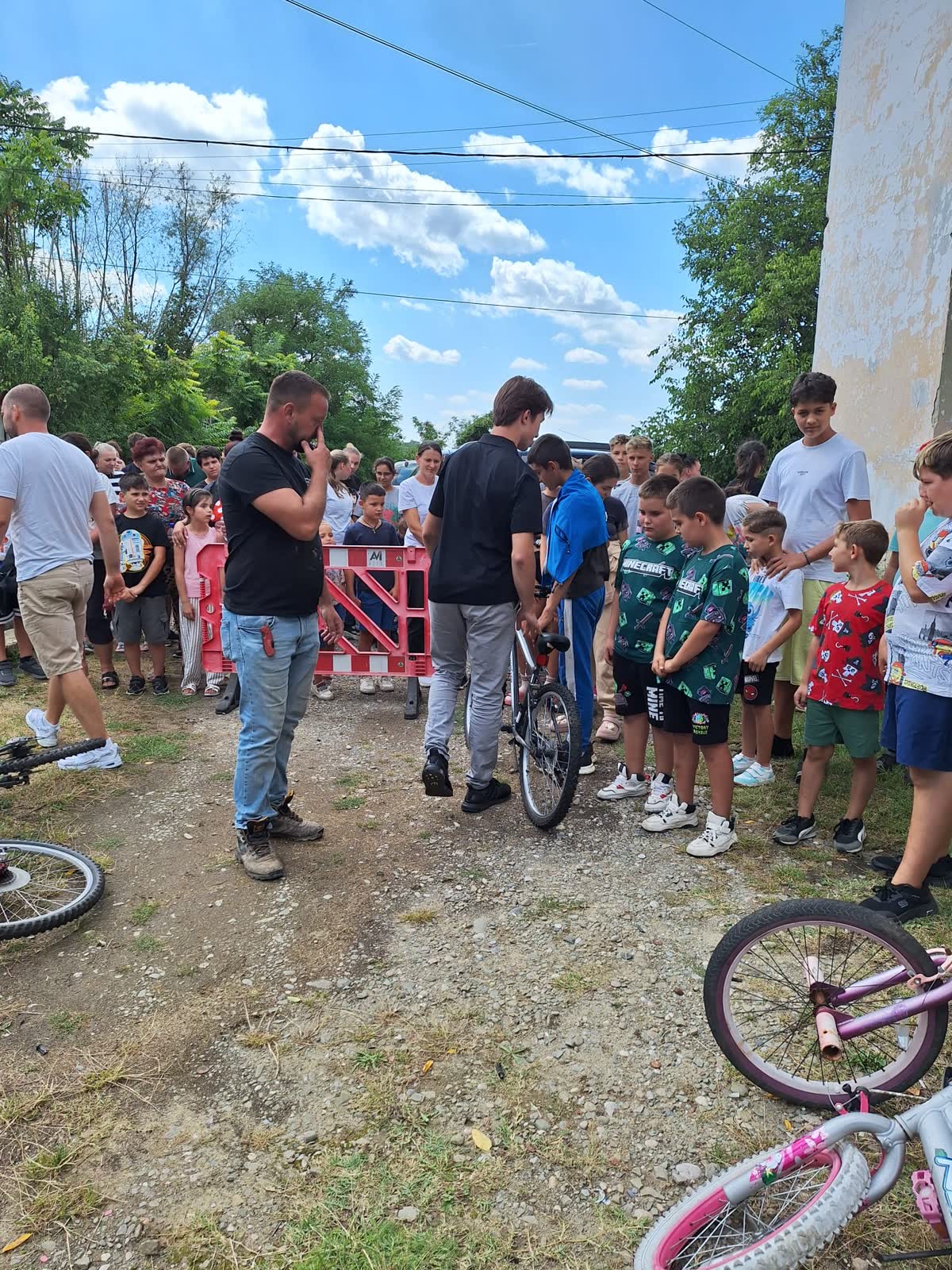 A police officer and community members address a large group of children before the bike handout.