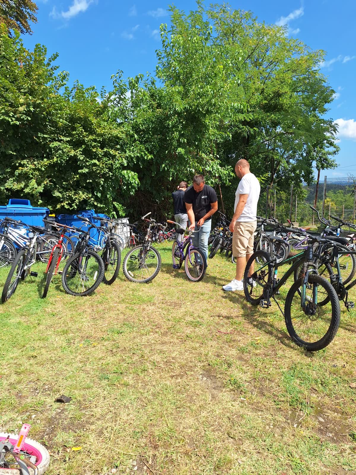 Volunteers adjusting a bicycle before handing it to a child.