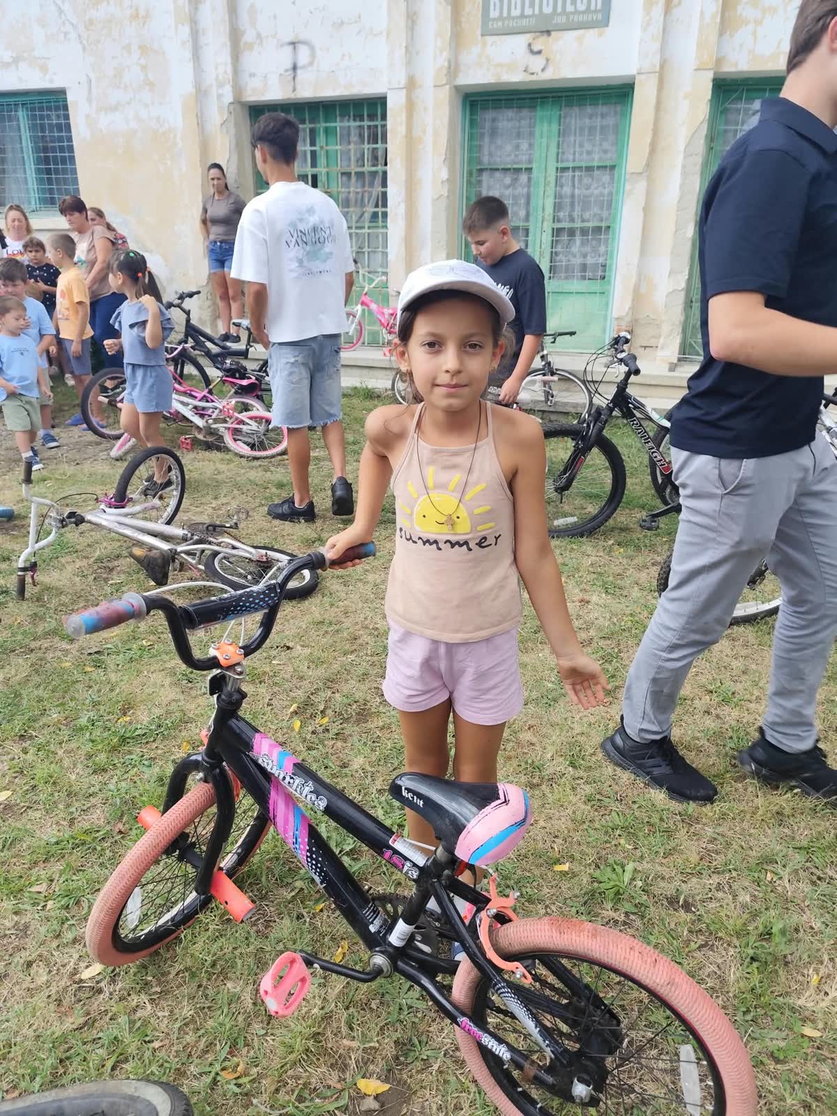 A young girl posing with her new bicycle outside the community center.