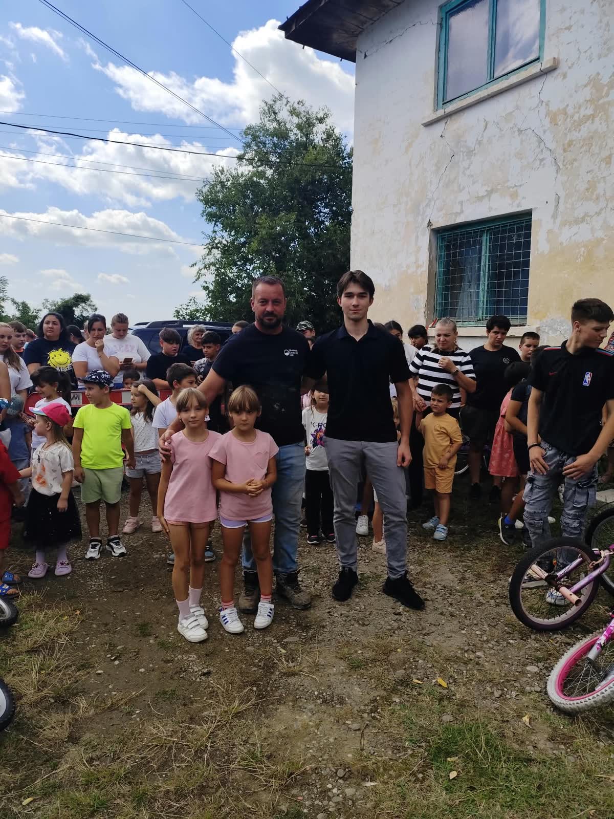 Volunteers posing with two young girls in front of the community building.