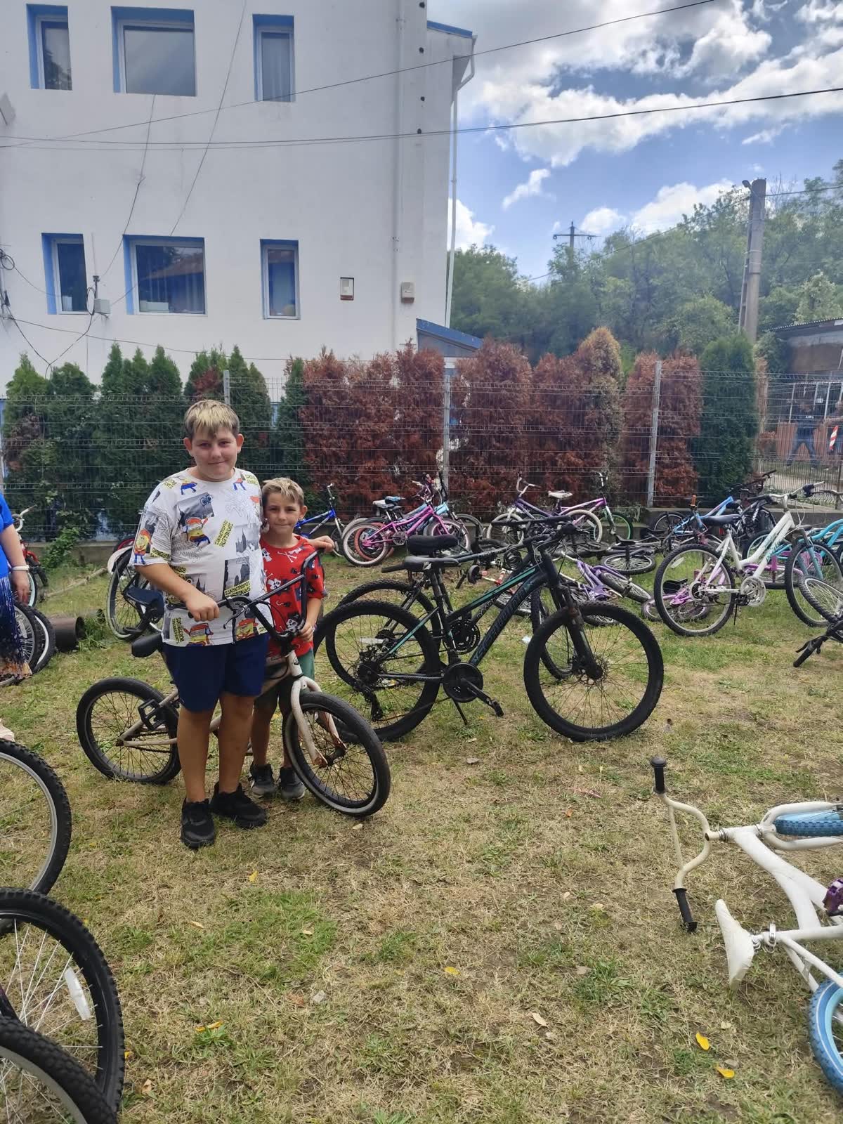 Two boys walking together with a bicycle.