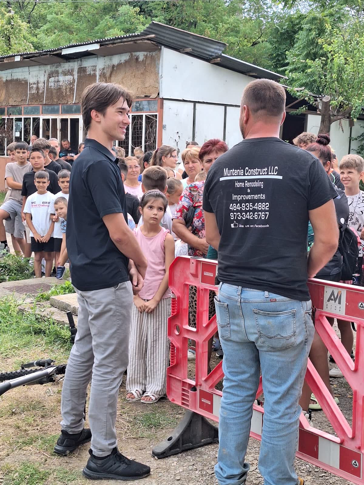 A volunteer speaking with a local partner as children look at bicycles in the background.
