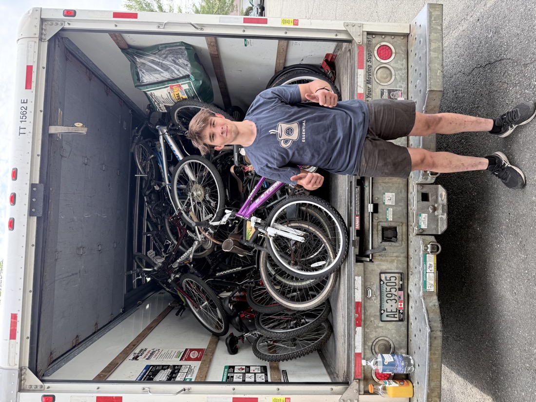 A volunteer giving a thumbs up inside a second U-Haul truck loaded with more donated bicycles.