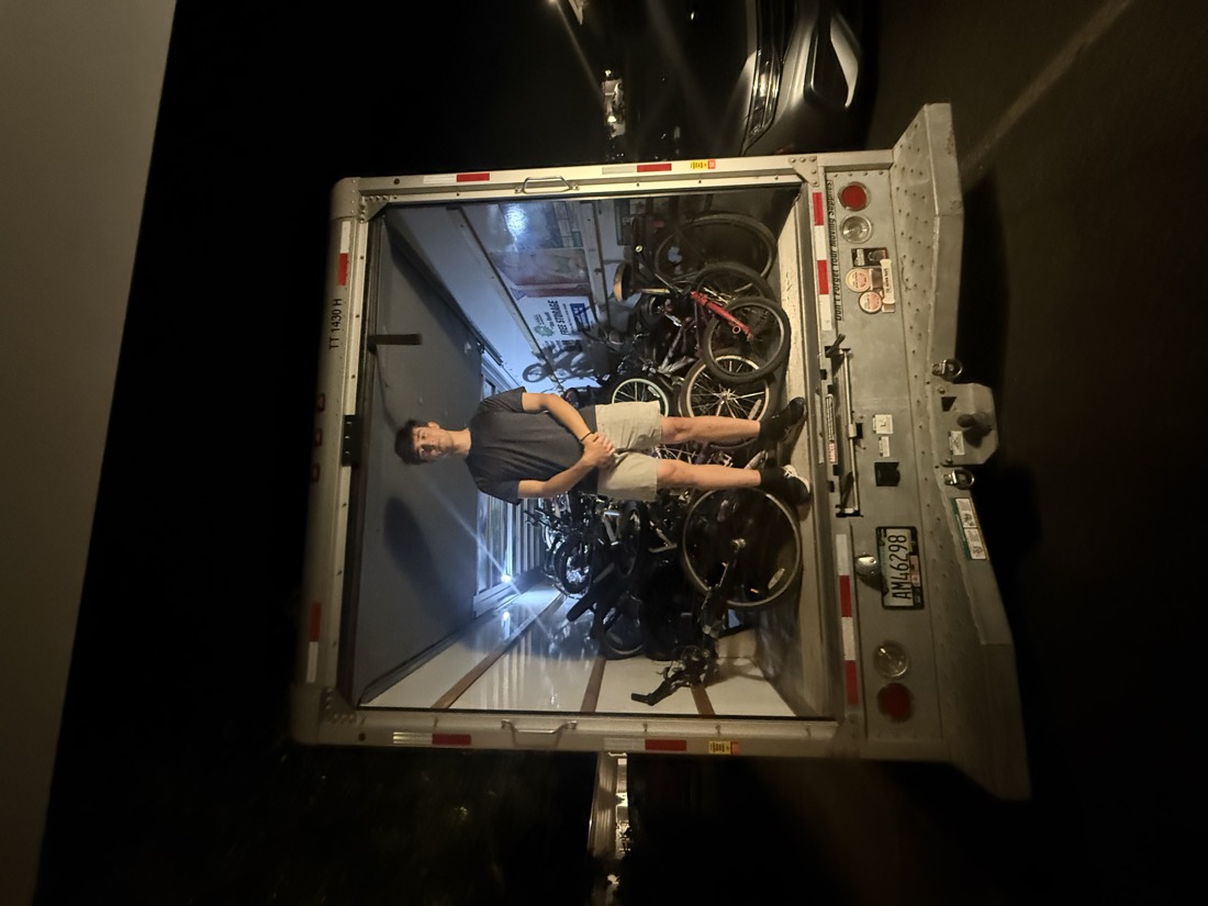 A volunteer standing inside the U-Haul truck, completely packed with bicycles, at night.