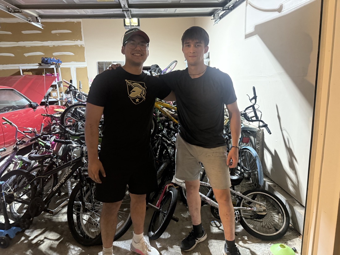 Volunteers at the garage door with a huge pile of donated bicycles collected that day.